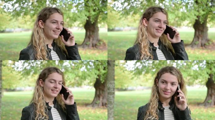 微笑的青少年在公园里用智能手机说话