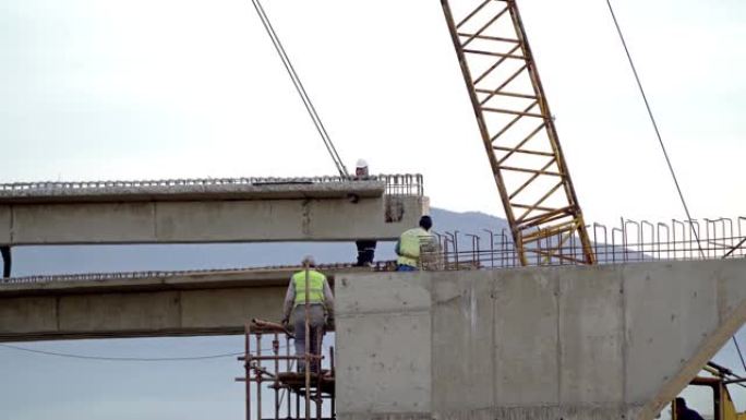 桥梁施工中的移动式起重机，道路交叉口桥梁上的工人和土木工程师