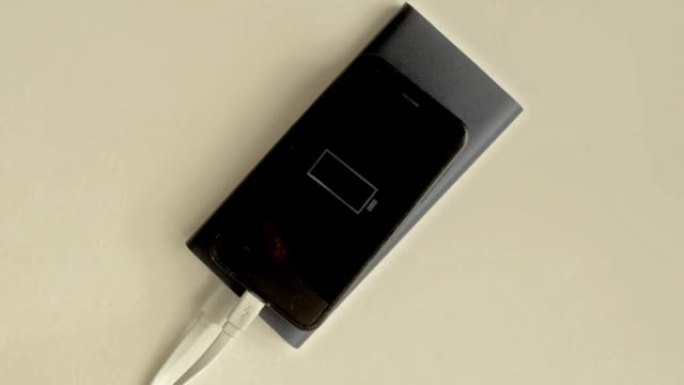 黑色智能手机正在通过移动电源充电，充电指示灯闪烁。