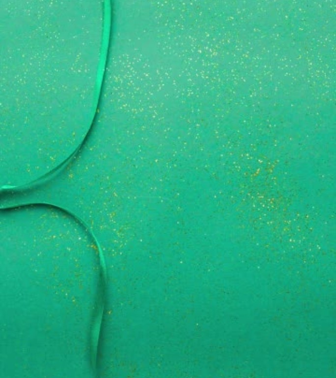 翡翠绿色缎带蝴蝶结，用金色闪光绑在绿色上并解开。停止运动垂直动画圣诞假期，并呈现概念平铺与复制空间