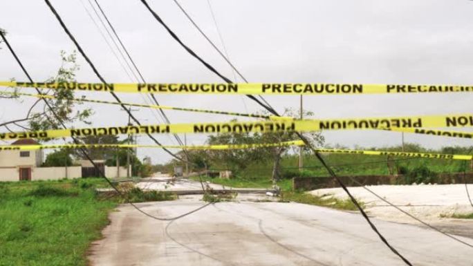 警告热带飓风过后，黄色胶带围栏在掉落的电力线电缆前随风摇曳。自然灾害的后果