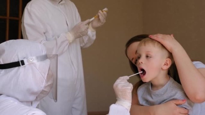 穿着防护服的医务人员从一个受感染的孩子身上拿了咽拭子。