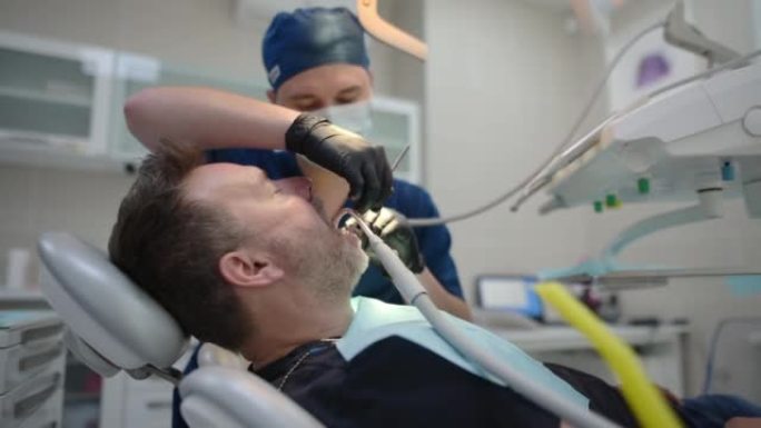 医生使用牙科工具为成熟男人的牙齿进行专业的口腔卫生