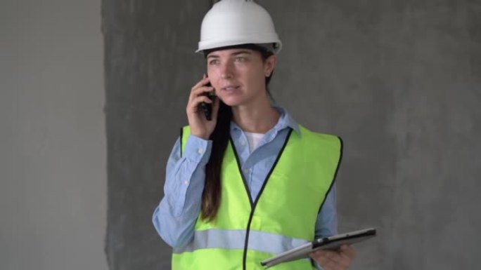 在室内使用平板电脑并在手机上聊天的建筑工地上从事项目的女工程师