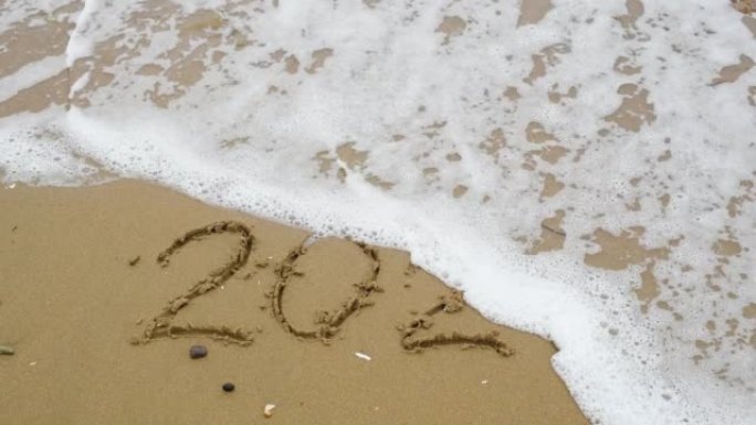数字2022写在被波浪冲走的沙子上。新年2023就要到了。圣诞节或新年概念
