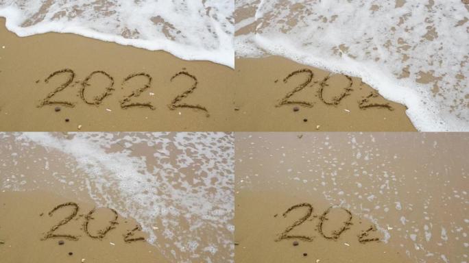 数字2022写在被波浪冲走的沙子上。新年2023就要到了。圣诞节或新年概念