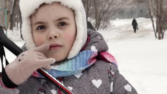一个冬天穿着滑雪服，手里拿着棍子的小女孩，她的嘴唇上有疮，冬天脸上有疱疹，免疫力下降。疱疹病毒引起的
