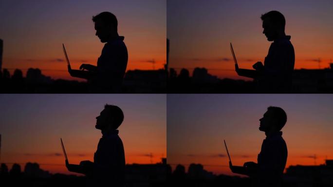 日落时户外使用笔记本电脑的显影剂男性剪影，工作，4K
