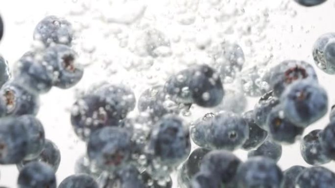 蓝莓以慢动作落入干净的水中。