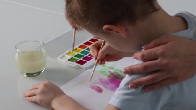 女人在幼儿园教孩子用画笔画画。