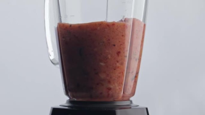 水果浆果鸡尾酒混合在搅拌机特写。有机混合物在混合器中旋转