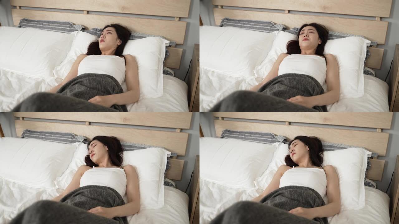 被毯子覆盖的沮丧的亚洲女孩醒着躺在卧室的床上，不想早上在家起床上班。