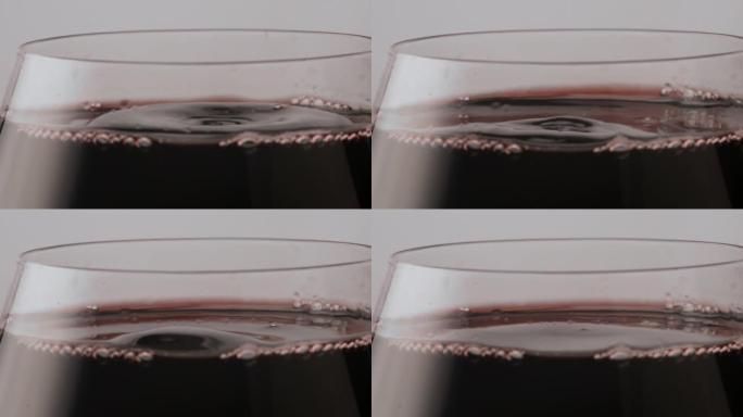 特写红酒滴落在光滑的酒精饮料表面。梅洛滴。
