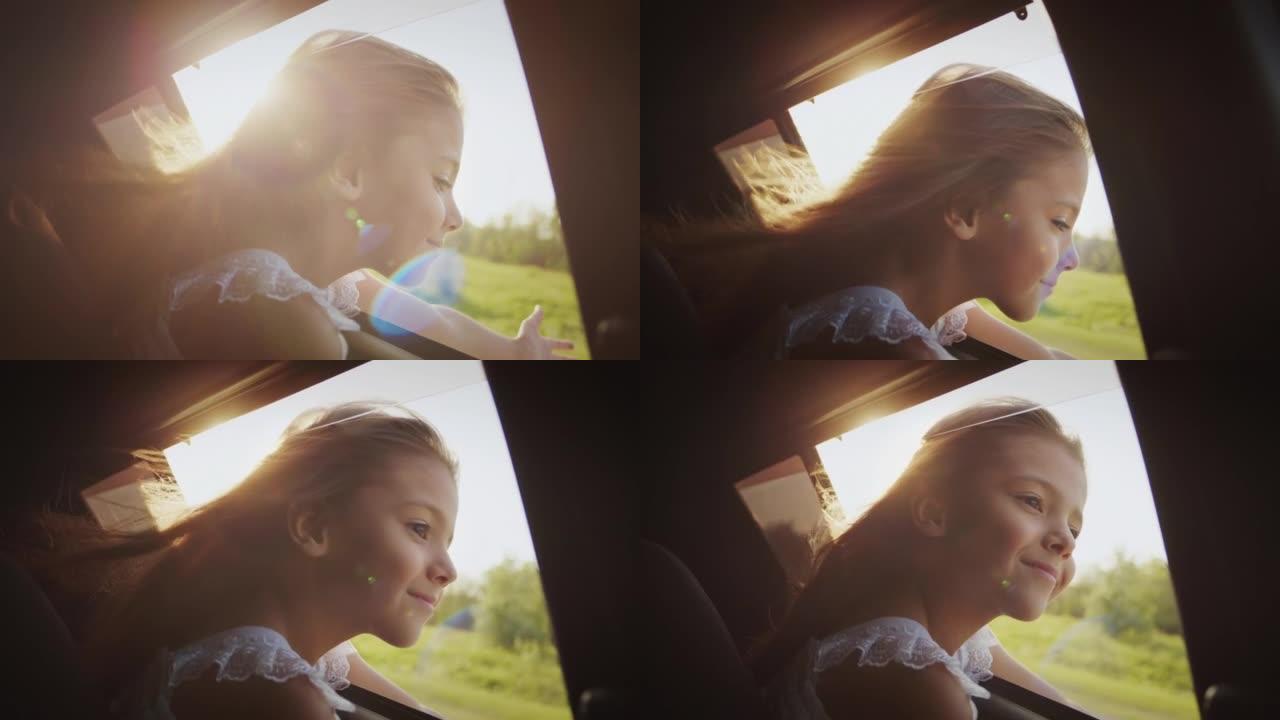 快乐的女孩坐在汽车后座上，用手迎风