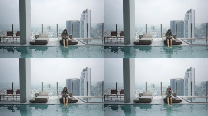 数字游民使用他的智能手机，坐在曼谷一家豪华酒店的游泳池-静态