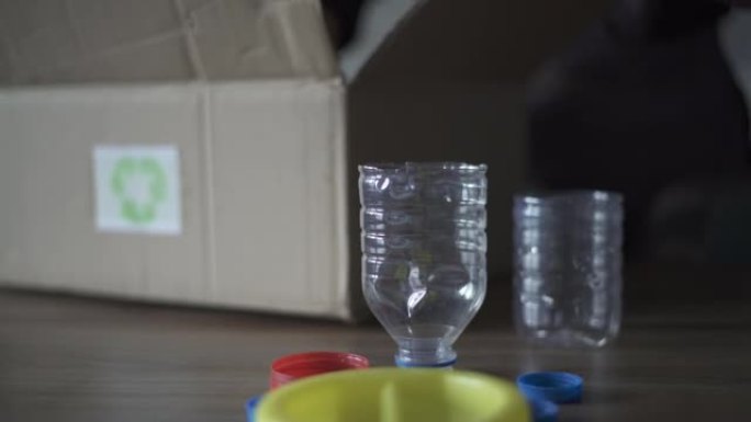 成年妇女将塑料瓶扔进厨房的回收箱