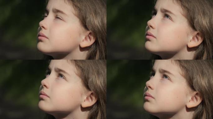 孩子仰望大自然的天空。肖像少女祈祷用希望和信念仰望天空，沉思的孩子脸，特写镜头。女孩仰望上帝信徒祈祷