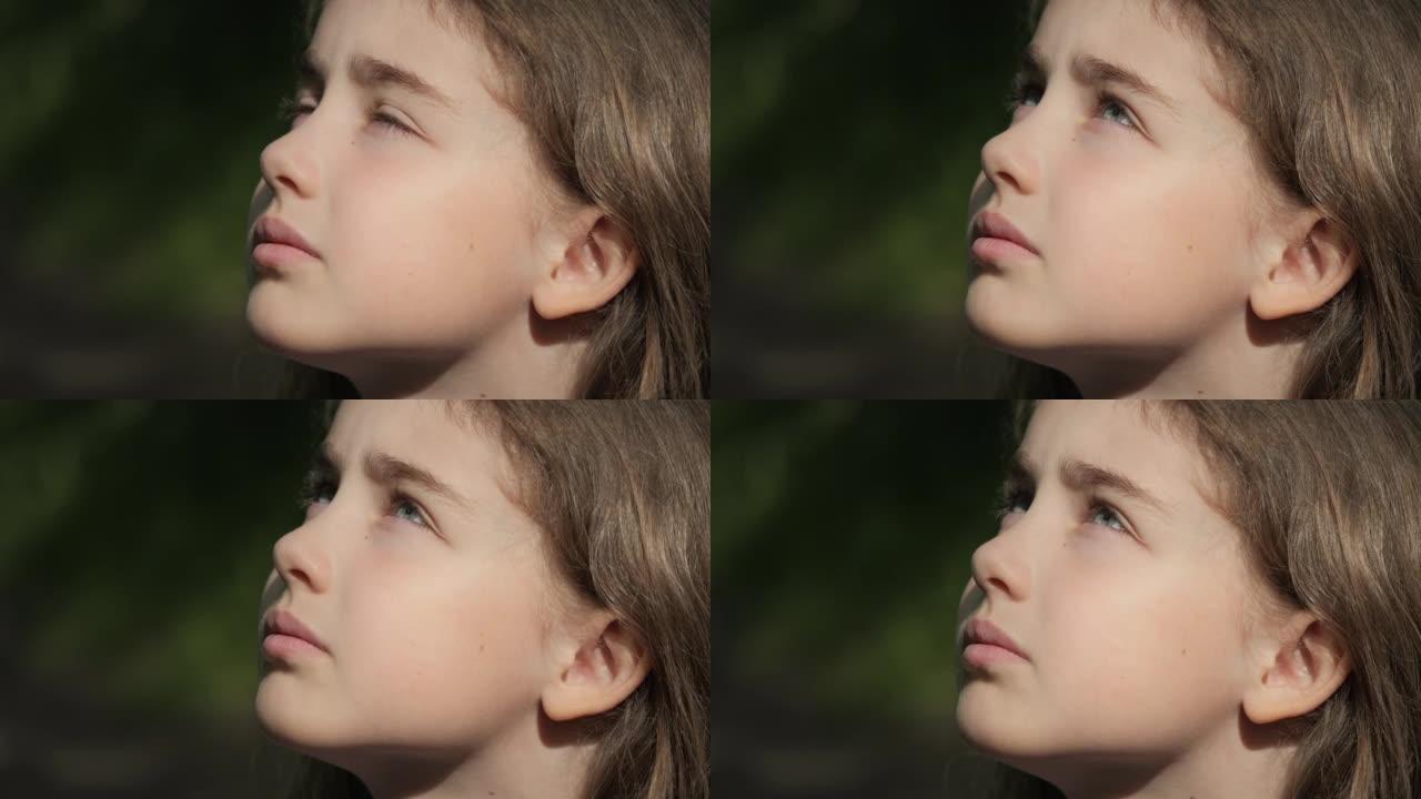 孩子仰望大自然的天空。肖像少女祈祷用希望和信念仰望天空，沉思的孩子脸，特写镜头。女孩仰望上帝信徒祈祷