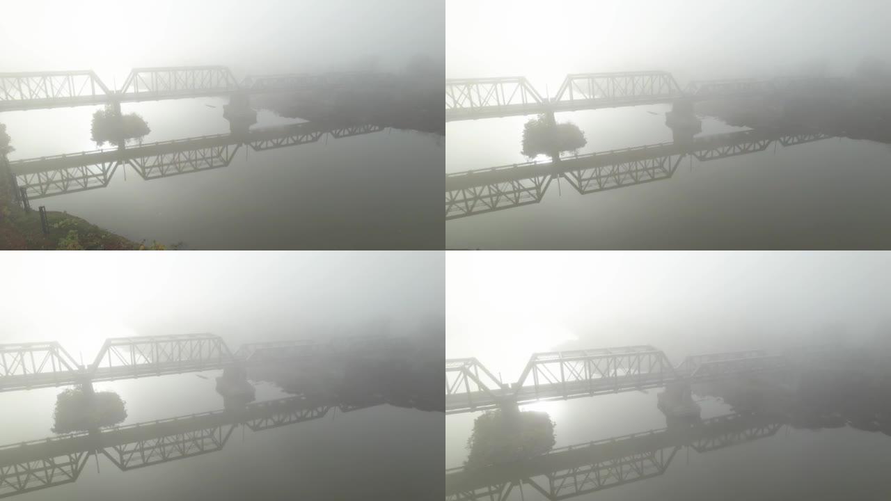 有雾和太阳耀斑的水上旧钢桥的鸟瞰图