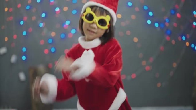 穿着圣诞老人服装的小女孩在圣诞节在家跳舞。
