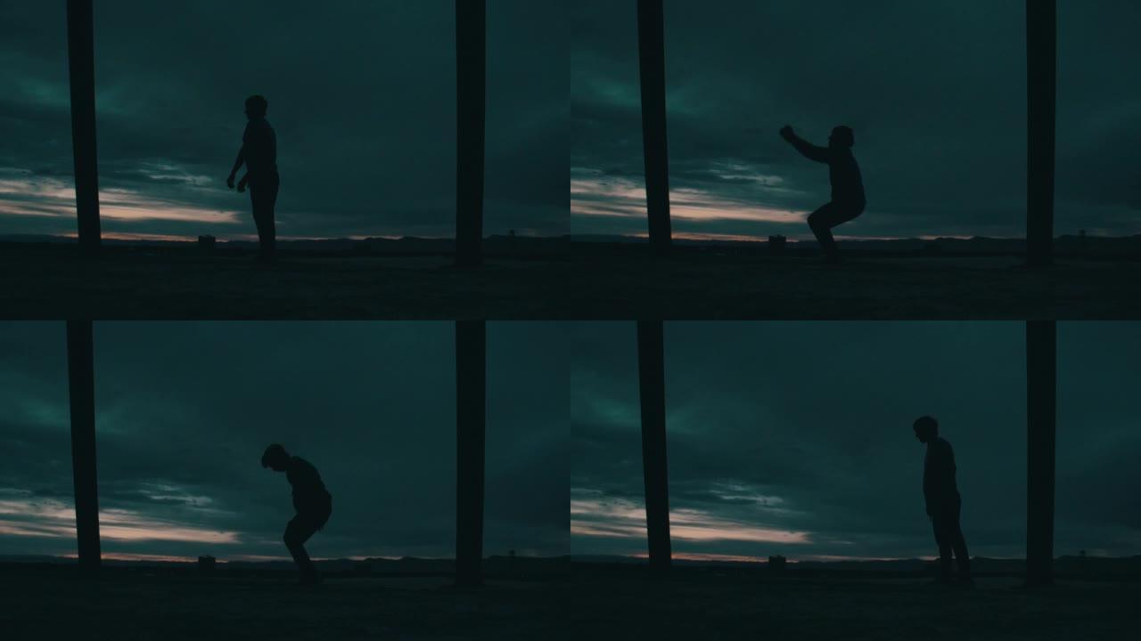 一个人在深蓝色的夜空下表演技巧和跑酷的剪影