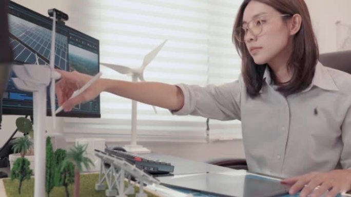 一名女工程师与计算机全息增强现实3D屏幕一起工作的视频，内容涉及工作室中用于替代能源的风车和太阳能电