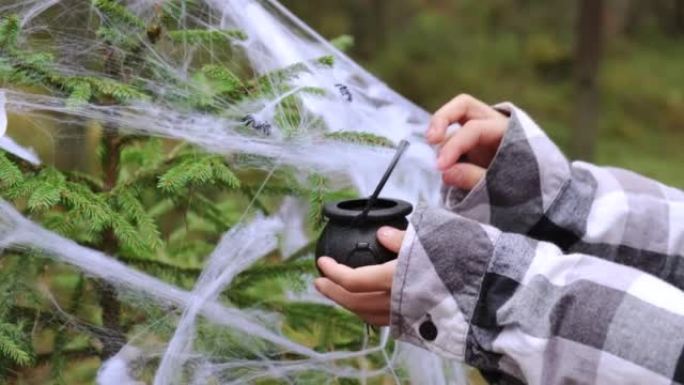 一个穿着格子衬衫的女孩打扮一棵圣诞树来庆祝万圣节，森林中的万圣节树装饰着蜘蛛网和可怕的装饰