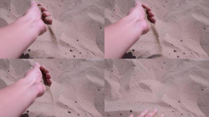 女性的手在阳光的照射下通过手指在海滩上倒沙