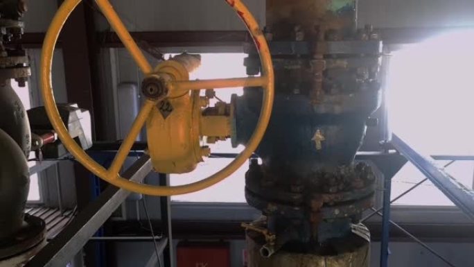 锅炉房的加热管上有一个黄色圆形方向盘的旧阀门。