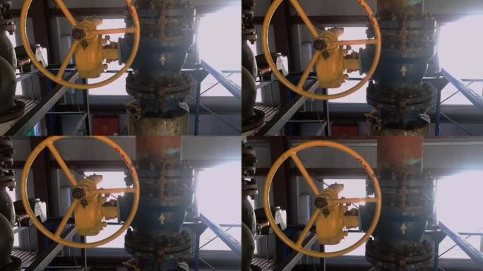 锅炉房的加热管上有一个黄色圆形方向盘的旧阀门。