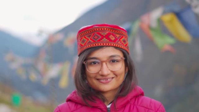 站在喜马拉雅山脉背景下，戴着喜马偕里帽的聪明自信微笑的印度妇女的头像。迷人的青少年学生女孩看着相机，