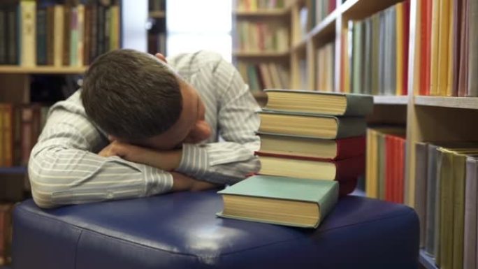 学生在准备考试的一排排书架之间睡着了。大学图书馆