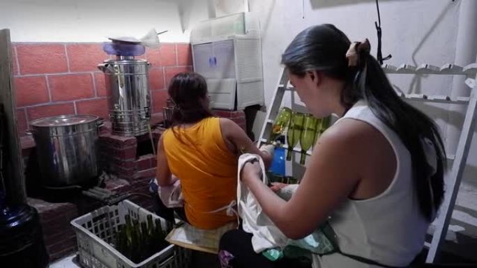 在当地一家小型酿酒厂的团队中工作的两个女人，一个是封盖瓶子，另一个是装瓶葡萄酒