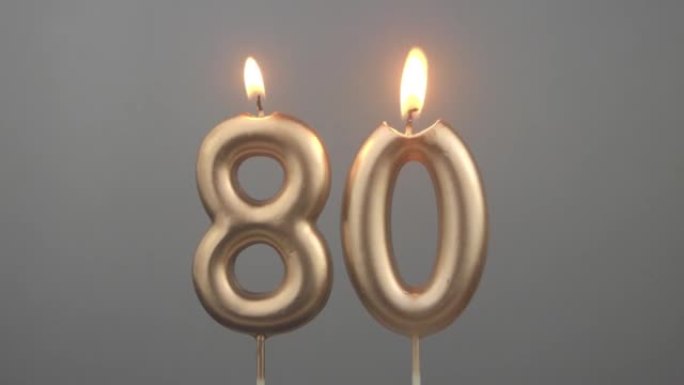 灰色背景上燃烧的金色生日蜡烛，80号