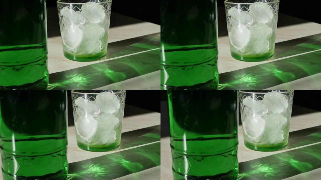桌子上是一瓶饮料和一杯绿色的玻璃，上面放着被明亮的太阳照亮的冰块，并在桌子上形成尖锐的阴影。多莉·格