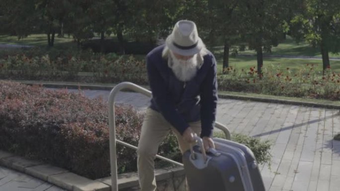 一个带着沉重的手提箱度假回来的高级男性成年人