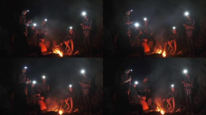 一群年轻人在黑暗中的篝火旁野餐