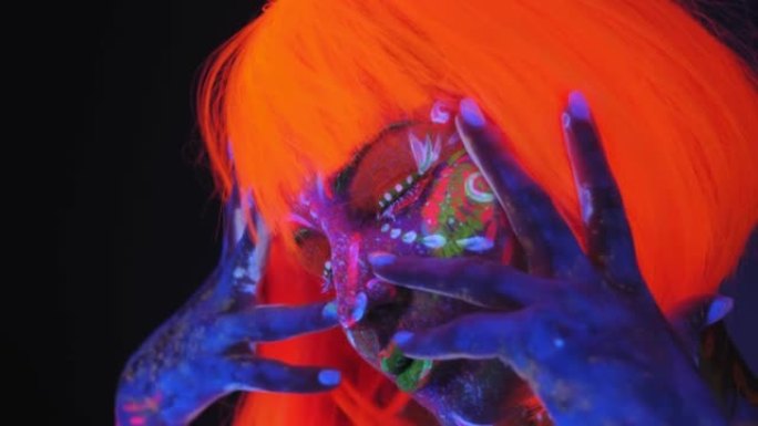 在荧光灯的照射下，一个画着紫外线图、戴着橙色假发的女孩。