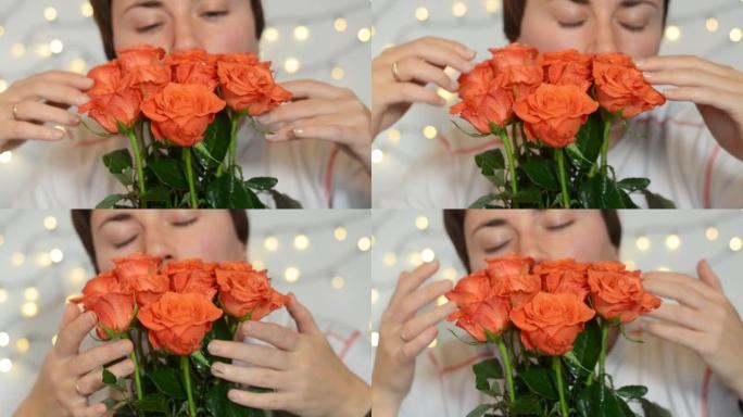 短发的年轻幸福的女人坐着一束红玫瑰。女孩轻轻地触摸花朵，闻到它们的香味。生日快乐。妇女节快乐。