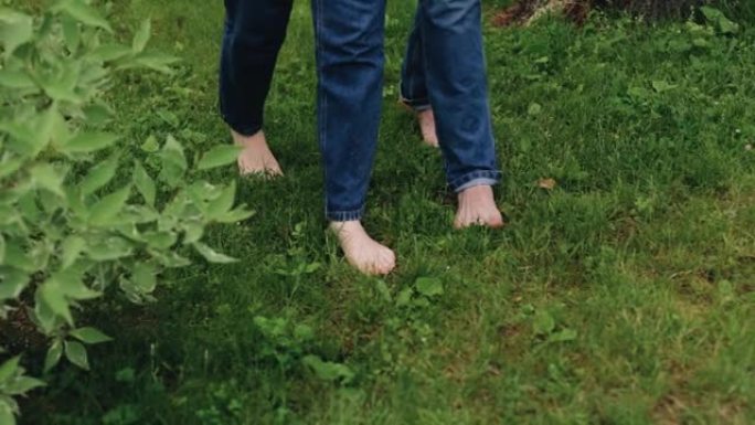 赤脚走在草地上的恋人的脚。相机以慢动作拍摄特写