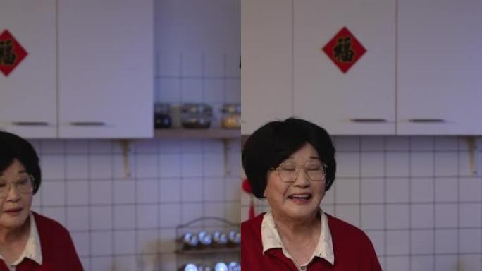 竖屏:中国农历除夕夜，在厨房吃完晚饭后，快乐的亚洲老年母亲尴尬地微笑着接受成年儿媳的压岁钱。翻译:幸