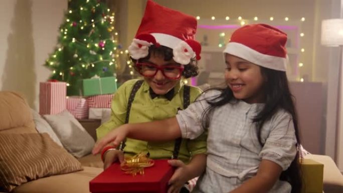 一个快乐的印度孩子在圣诞节前夕在装饰房屋中收到礼物