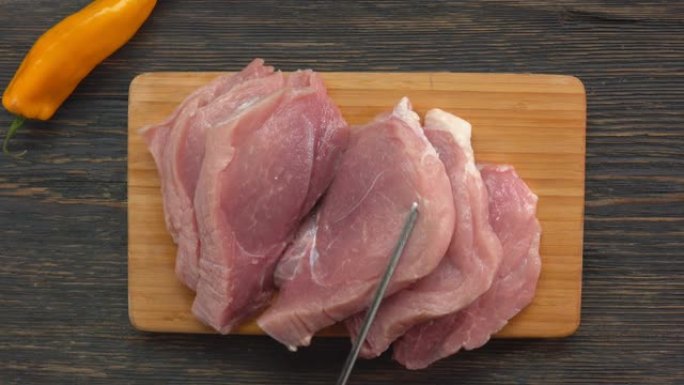 刀在木板上转动生猪肉肉排的俯视图