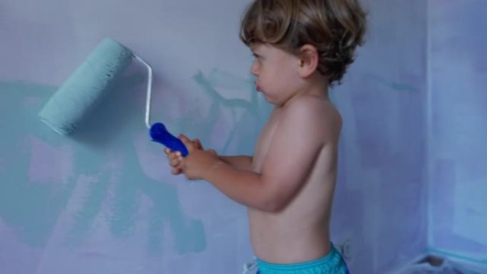 带油漆滚筒的儿童粉刷墙。可爱的小男孩用设备画画。孩子帮助父母进行房屋翻新