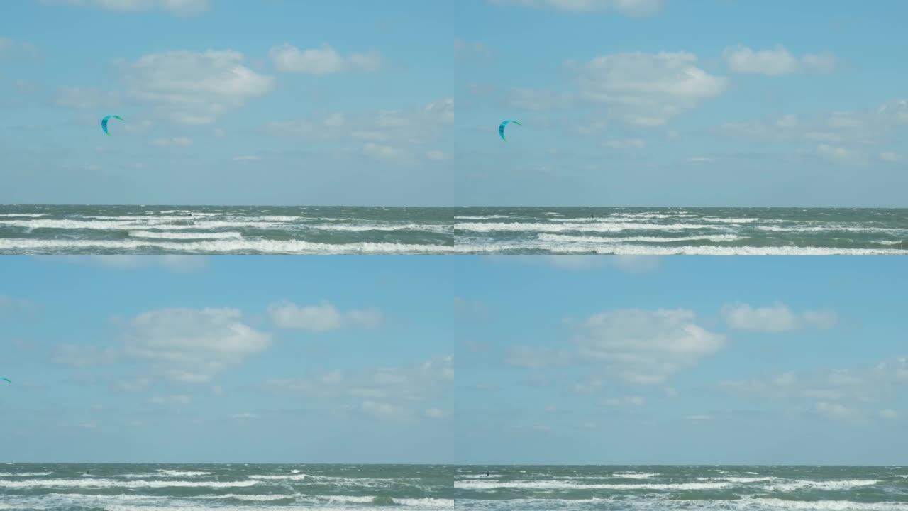 一个穿着潜水服的女人穿着降落伞在海浪中滑行。一个年轻人在空中对着天空表演魔术。水上运动，风筝冲浪，滑