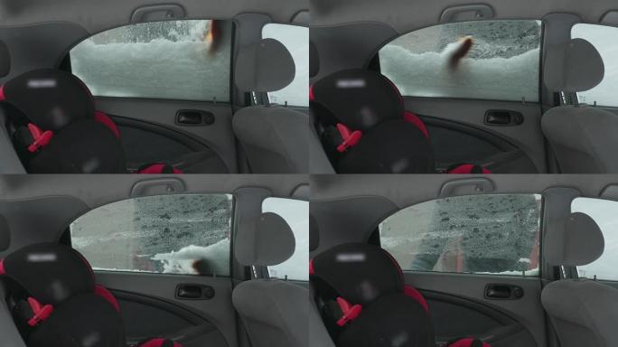 车主将汽车后门的窗户从雪地上清洗干净。