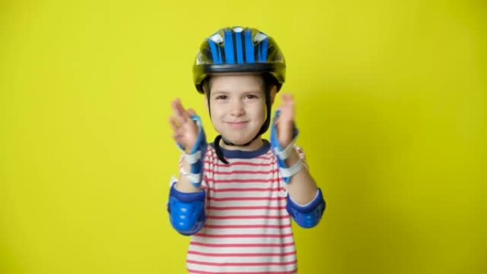 黄色背景上戴着防护头盔、护肘和手套的小男孩 -- 骑自行车、滑板、旱冰鞋时的保护