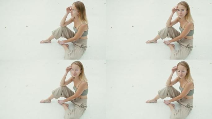 白癜风色素沉着的漂亮年轻女子坐在白色地板上，看着相机