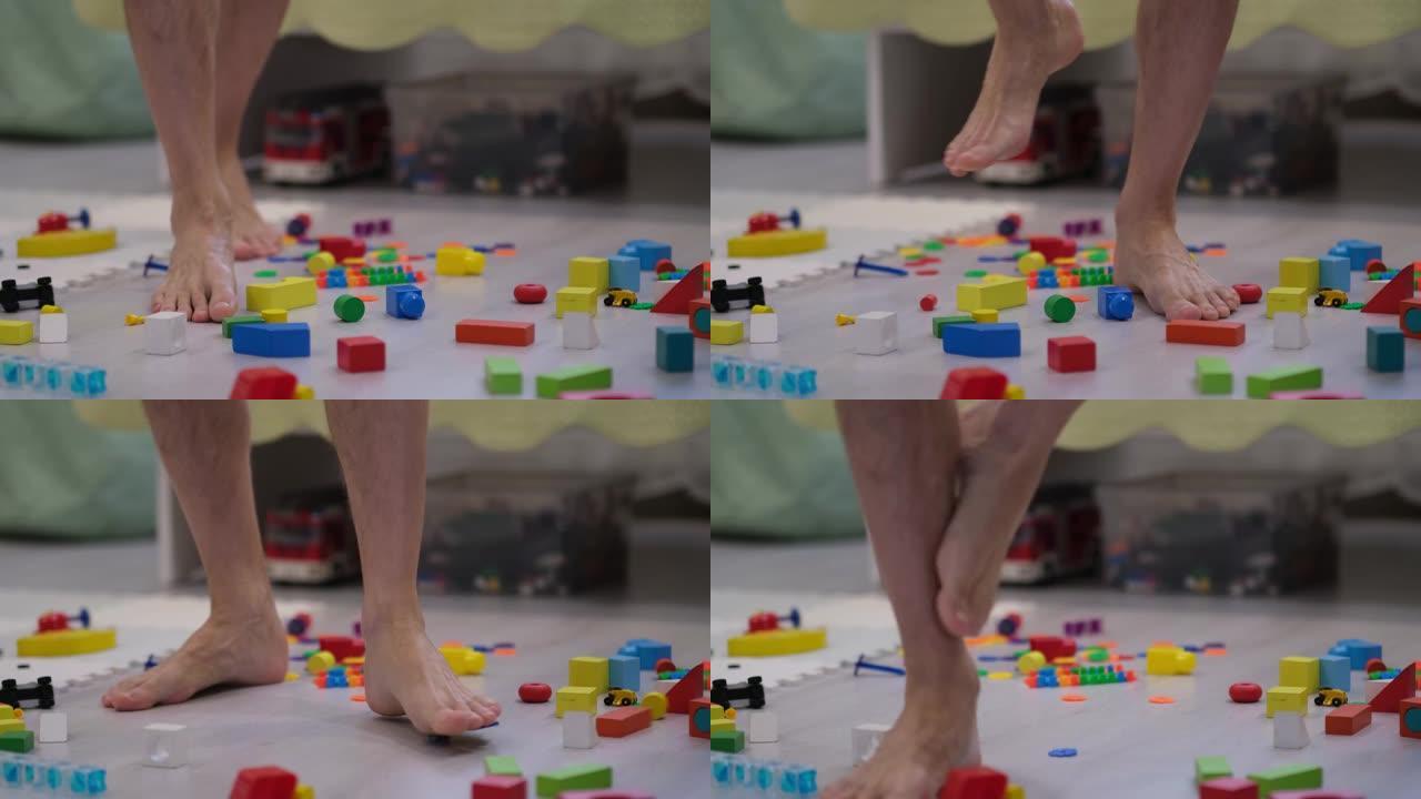 脚踩在儿童玩具上。散落在地板上的玩具。男子被儿童玩具绊倒的特写镜头