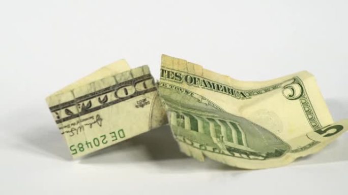 美元钞票的详细宏观纹理的幻灯片。白色背景上损坏的钞票的慢速美元拍摄。法定货币概念。撕裂和皱巴巴的钞票
